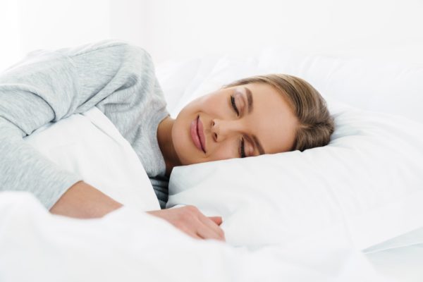 Image closeup of cute young woman lying and sleeping in bed